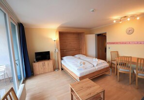A hotel room with a bed, a TV, a desk, a chair, and a dining table.