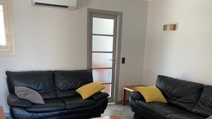 A living room with two black leather sofas, a wooden coffee table, and a tiled floor. - Villa with pool (Canet-en-Roussillon)