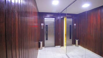An elevator with a metallic interior and a wooden wall.