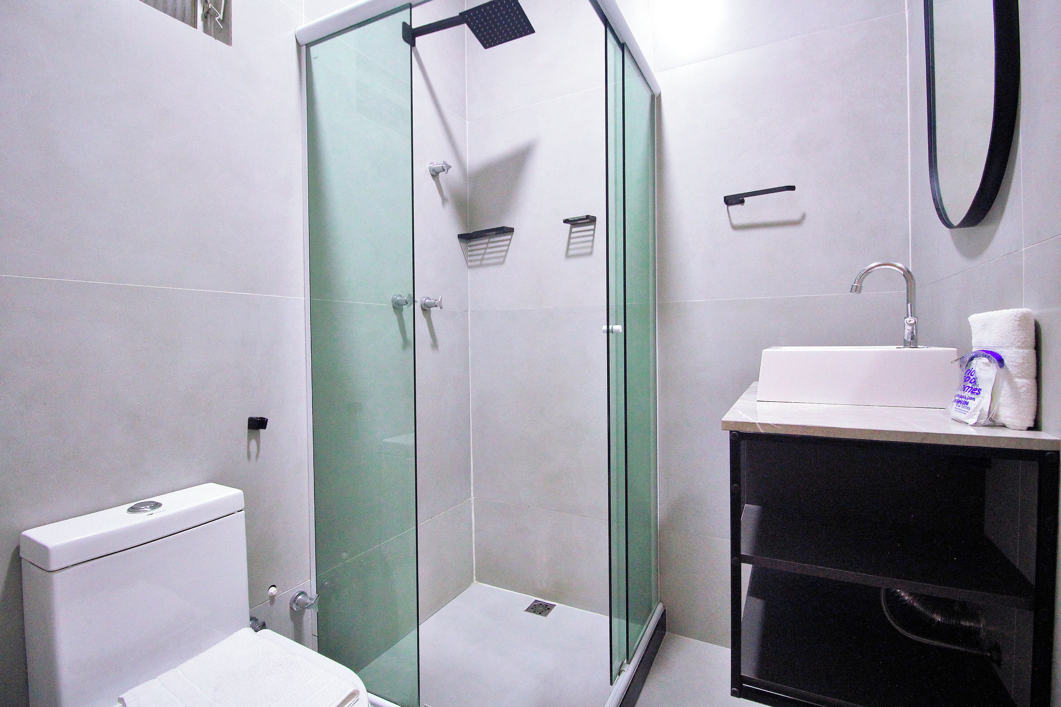 A modern bathroom with a glass-enclosed shower, a white sink, and a toilet.