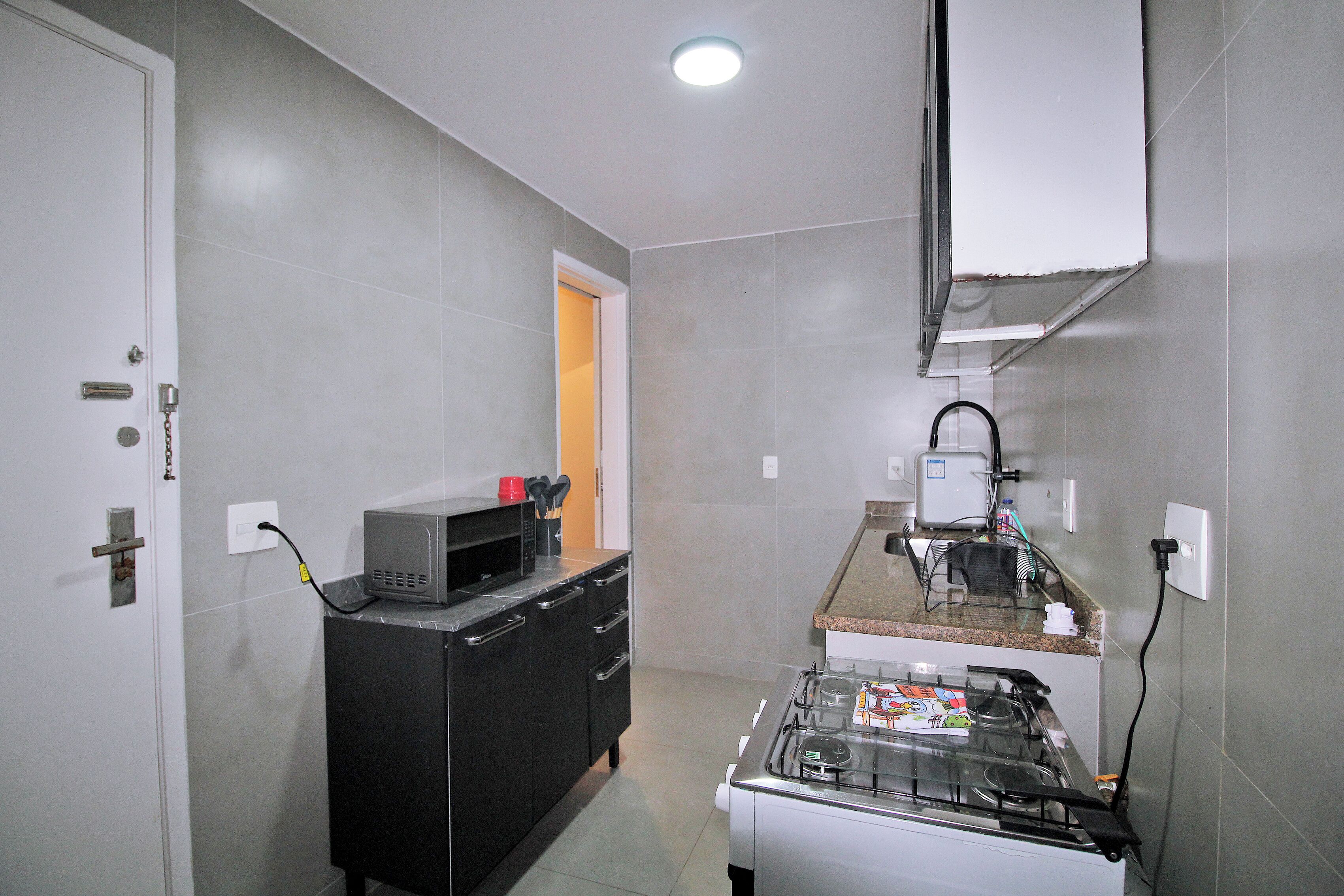 Una cocina compacta con estufa a gas, microondas y un refrigerador pequeño.
