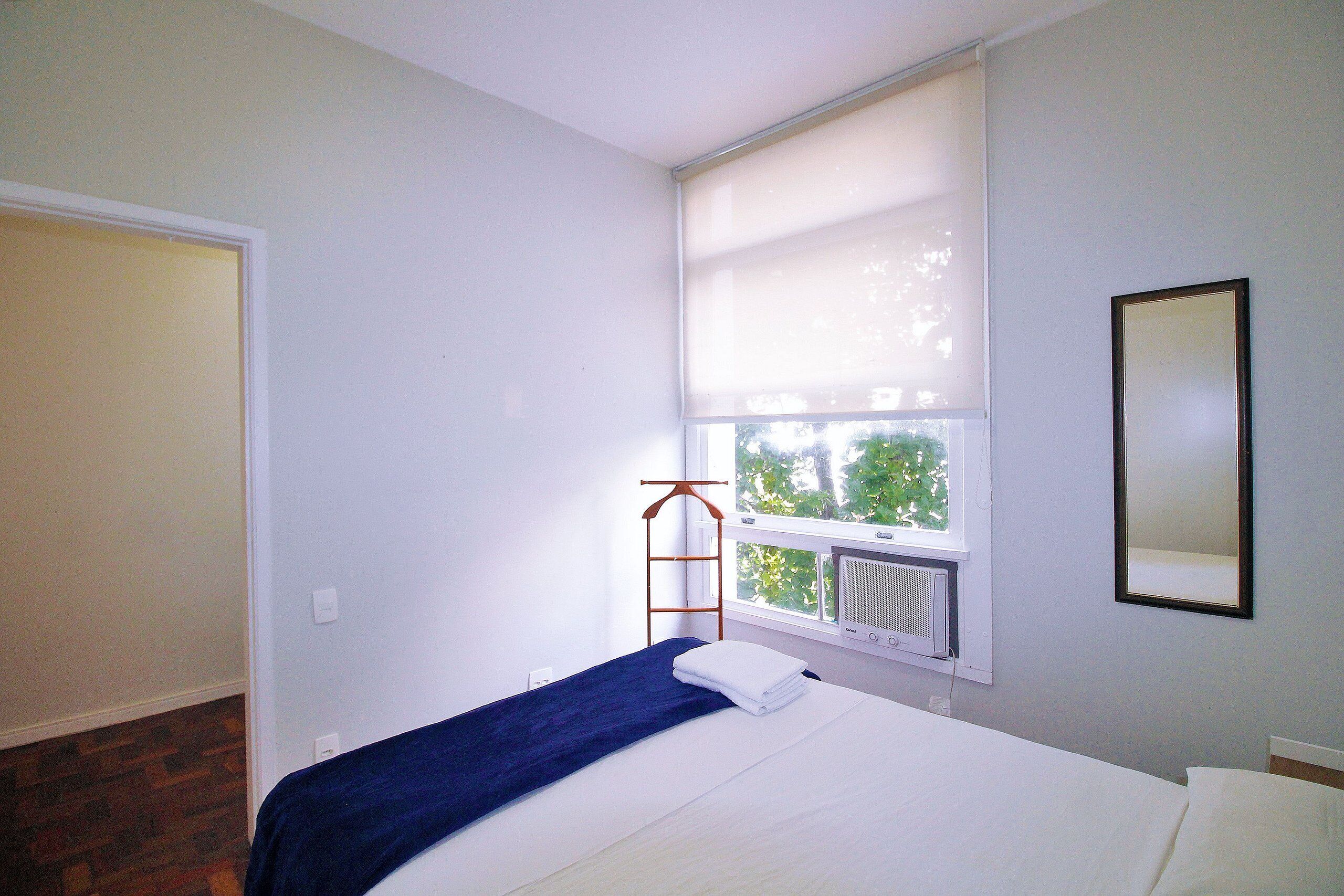 Une chambre à coucher avec un lit, une fenêtre avec des stores, un radiateur et une échelle en bois.