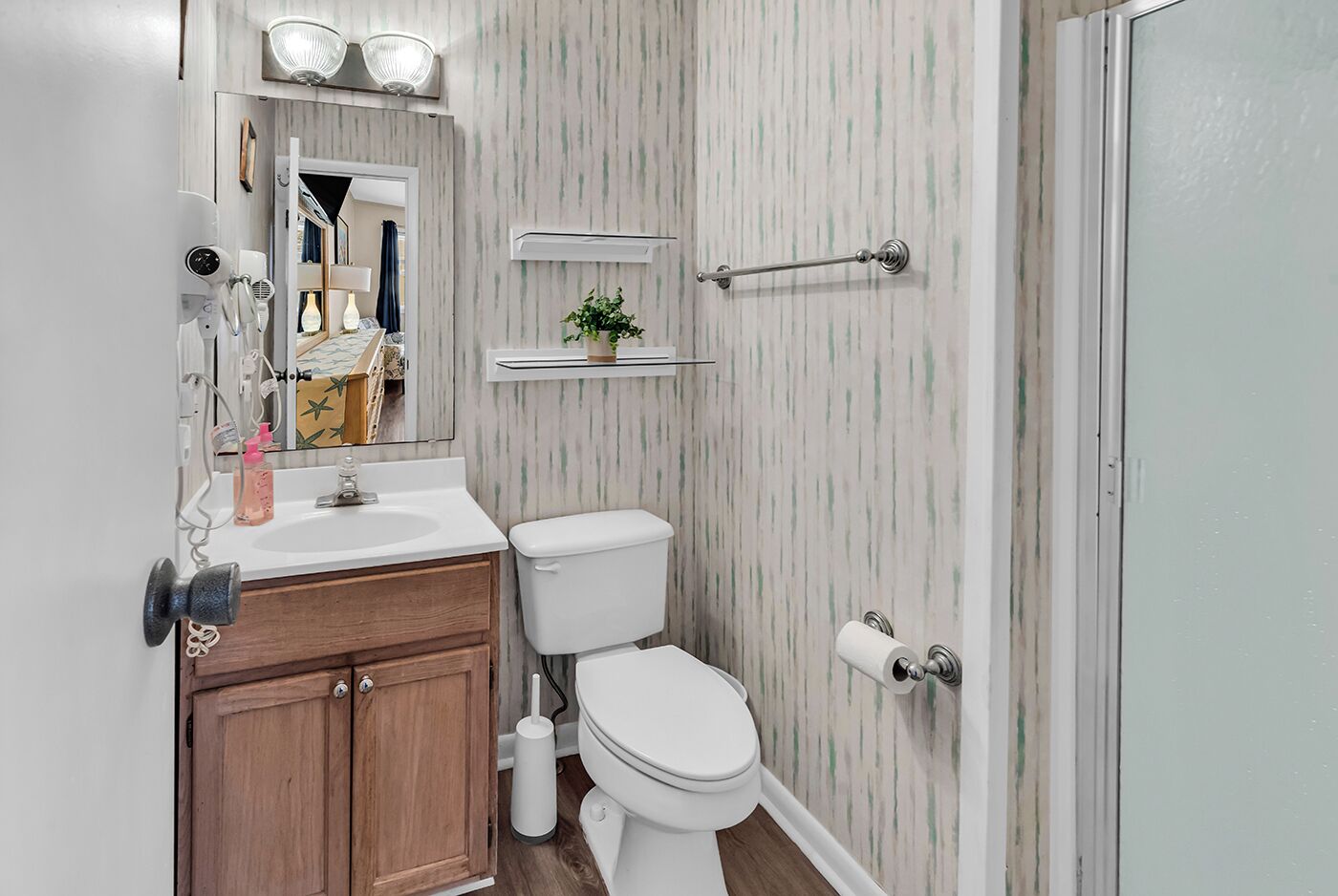 Une salle de bain avec un meuble-lavabo en bois, des toilettes, un miroir et un espace douche.