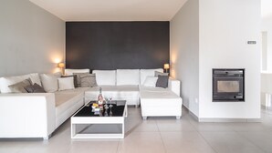 A modern living room with a white sofa set, a black coffee table, and a built-in fireplace. - Villa w/ Palm Trees & Pool (Saint geniès de Fontedit)