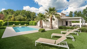 A pool area with a clear blue pool, palm trees, and lounge chairs. - Villa w/ Palm Trees & Pool (Saint geniès de Fontedit)