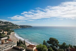 A coastal view with a beach, ocean, and buildings in the background. - Villa w/ Palm Trees & Pool (Saint geniès de Fontedit)
