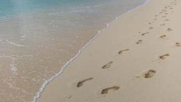 A sandy beach with footprints leading into the water.