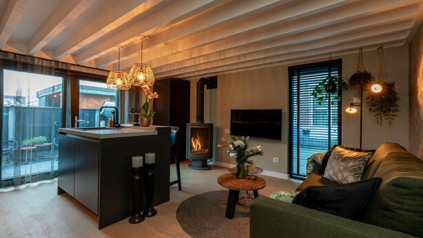 Un salon moderne doté d’un îlot central, d’une cheminée, d’un canapé et d’un téléviseur fixé au mur.