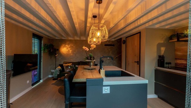 Een moderne keuken met een centraal kookeiland, een inbouwspoelbak en een hangende lamp.