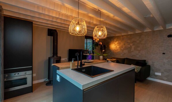 A modern kitchen with a built-in island, a stove, and pendant lighting. - Apartment in Zoutelande near the Beach (Zoutelande)