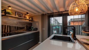 Een moderne keuken met een zwart aanrechtblad, een inbouwspoelbak en een hangende lamp.