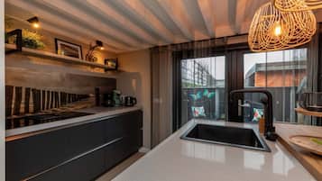 A modern kitchen with a black countertop, a built-in sink, and a hanging light fixture.