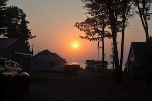Een woonstraat met huizen en geparkeerde auto's tijdens de zonsondergang.