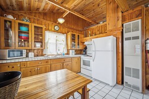 Una cocina de madera con armarios, microondas, refrigerador y pileta.