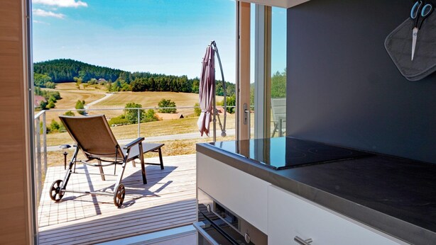 A balcony with a view of a rural landscape, a grill, and a pair of scissors hanging on the wall. - Ferienhaus, Sankt Georgen (Sankt Georgen OT Langenschiltach)