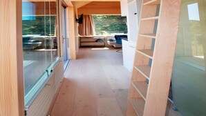 A modern interior with a wooden floor, glass sliding doors, and a seating area with a sofa and a chair. - Ferienhaus, Sankt Georgen (Sankt Georgen OT Langenschiltach)
