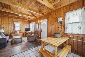 Un intérieur en bois comprenant un canapé, un fauteuil, une table et un téléviseur.
