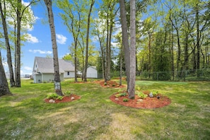 A residential property with a house, a garage, and a well-maintained lawn with trees and shrubs. - Cottage 2: A cozy lakefront cottage at Sunnyside — steps from the fire pit and shared beach. (Greenbush)