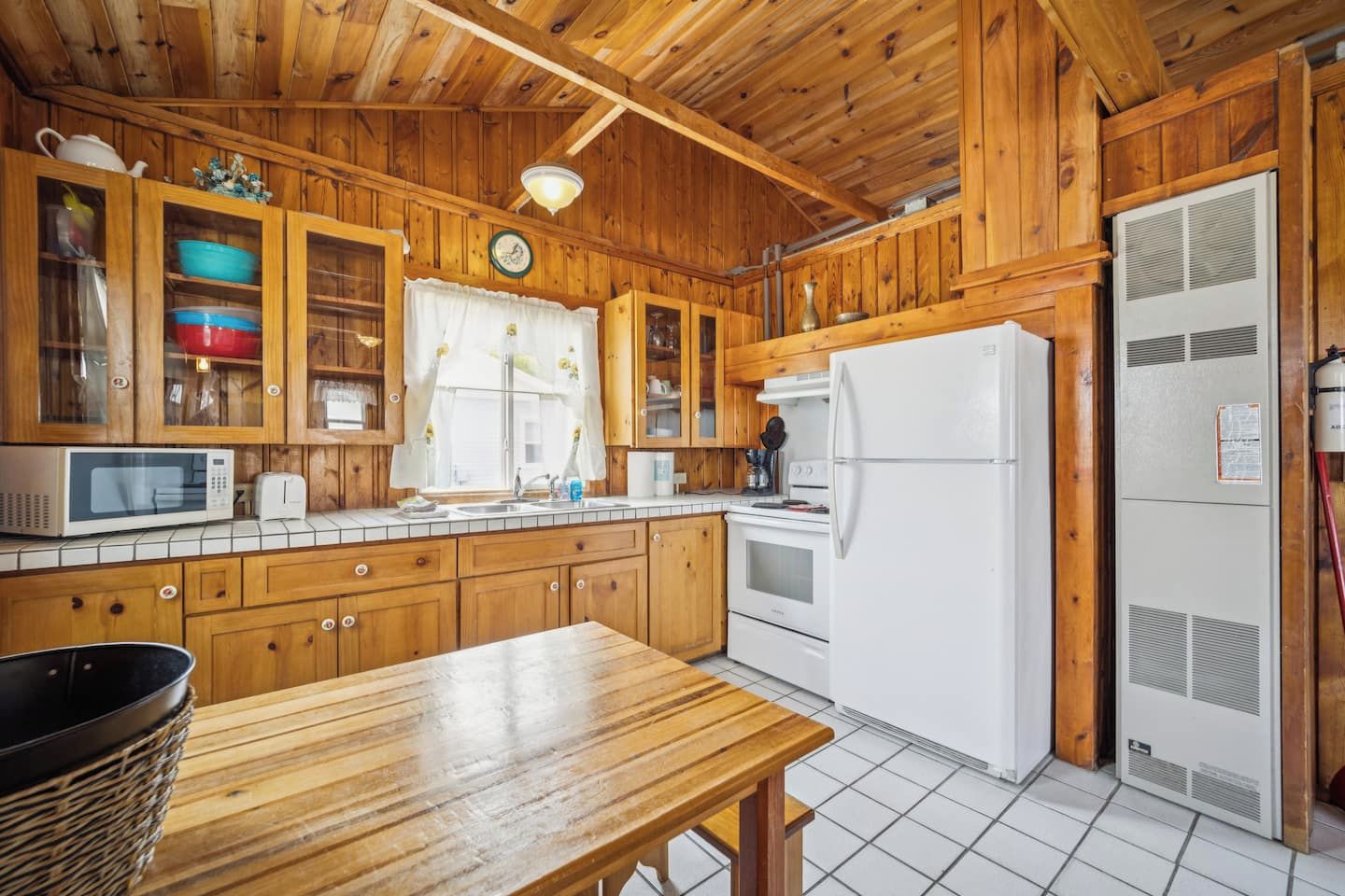 Una cucina in legno con forno a microonde, tostapane, lavandino e frigorifero.