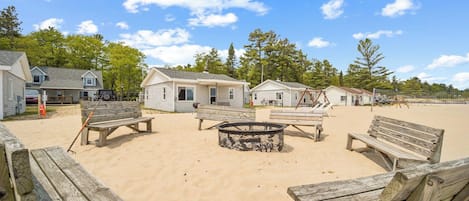 Una propiedad frente al mar con bancos de madera, una fogata y casas de playa.