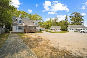 A residential street with houses, a paved driveway, and a clear sky. - Spacious Lakefront Cottage w/ AC (Greenbush)