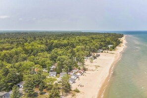 A coastal property with a beach, dense forest, and residential buildings. - 3BR/1BA lakefront cottage at Sunnyside with A/C, private beach access, and lawn games. (Greenbush)
