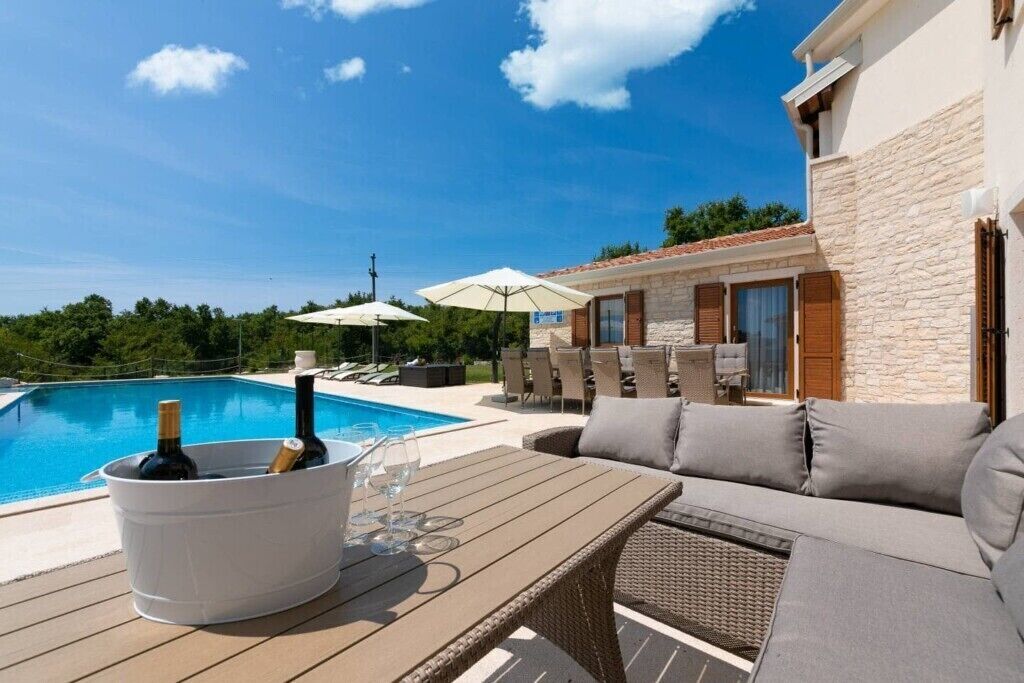 A poolside area with a table, chairs, and umbrellas.
