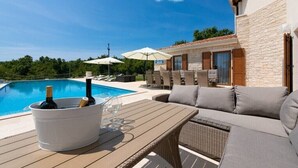 Un espace aménagé au bord de la piscine, avec une table, des chaises et des parasols.