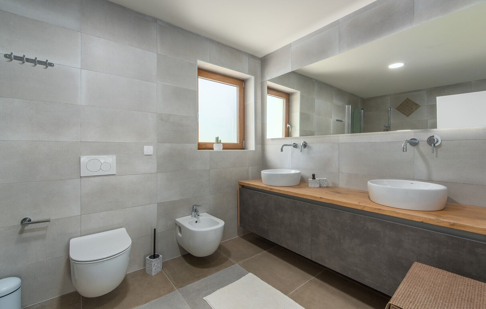 A modern bathroom with two sinks, a bidet, and a toilet.