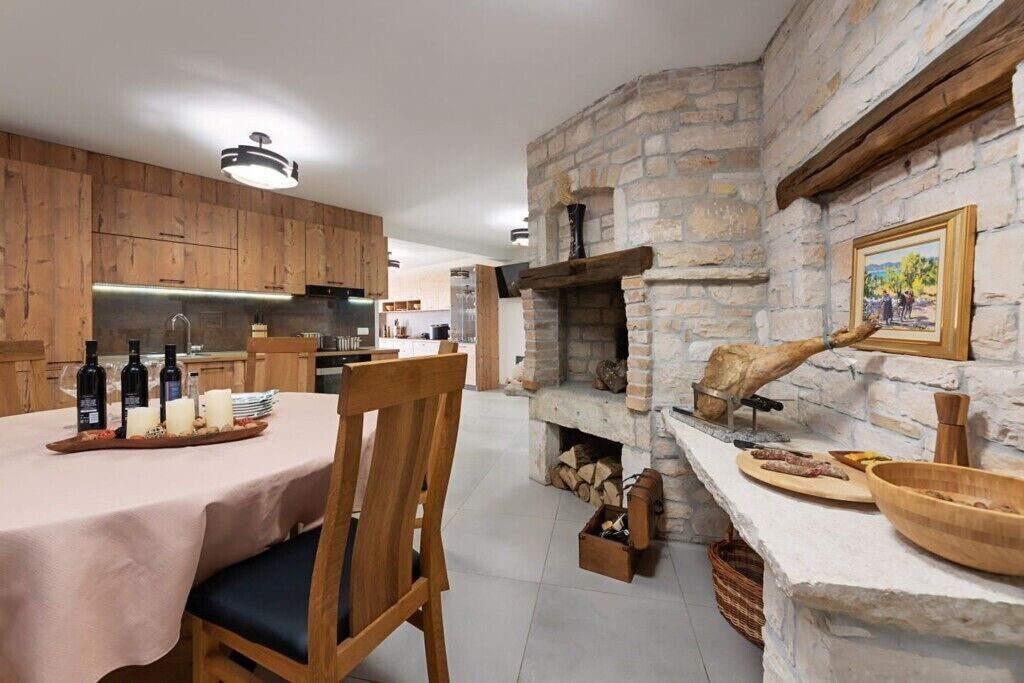 Una cocina rústica con armarios de madera, una chimenea de piedra y un comedor con una mesa dispuesta para una comida.