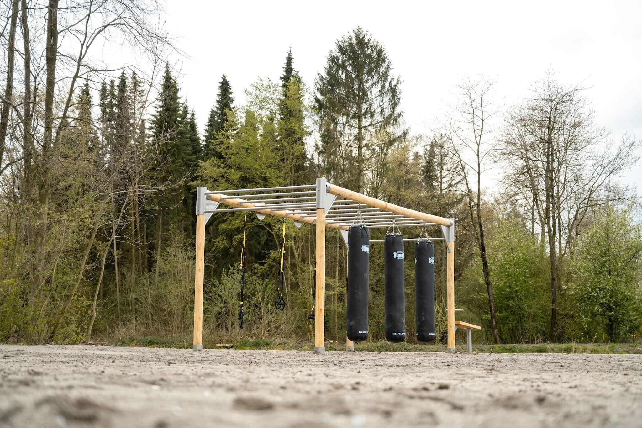 A wooden structure with a roof, possibly a gym or training area, surrounded by trees.