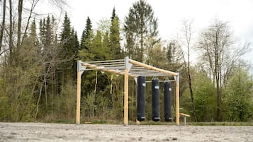 A wooden structure with a roof, possibly a gym or training area, surrounded by trees.