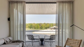 A modern room with a large window, a sofa, two chairs, and a small table. - Water Lodge in Netherlands with Paddleboarding (Zeewolde)
