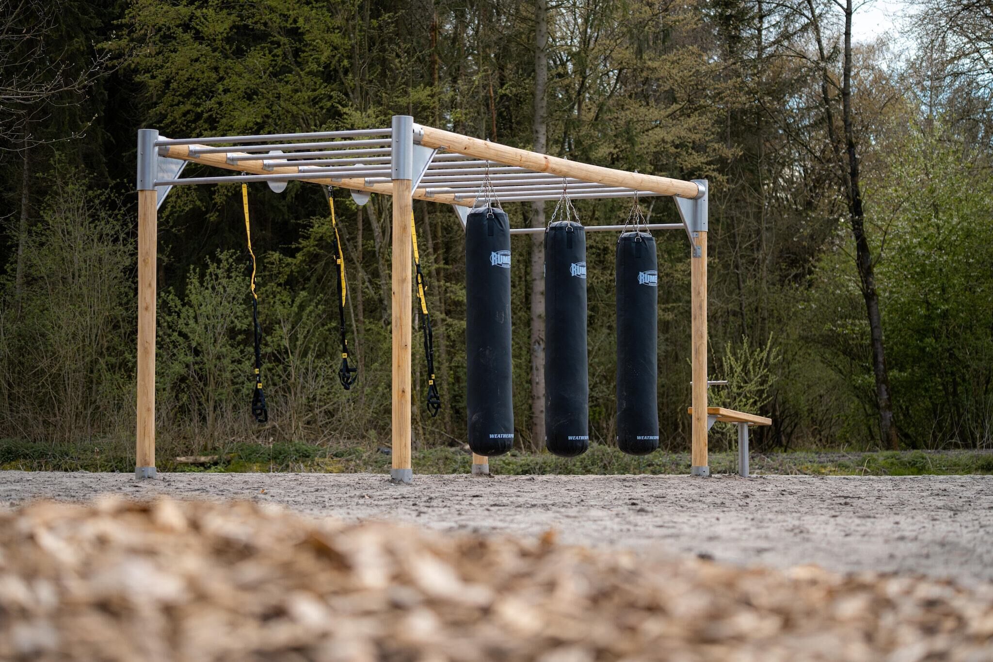 Ein Fitnessbereich mit einer Klimmzugstange und drei Boxsäcken.