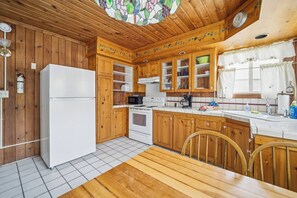 Une cuisine avec des meubles de rangement en bois, un réfrigérateur blanc, une cuisinière et un four à micro-ondes.