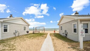 A pathway leading to beachside cabins with a sign indicating pets must be on a leash.