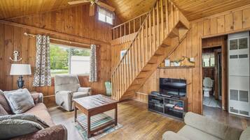 Un intérieur en bois avec un canapé, un fauteuil, un téléviseur et un escalier.