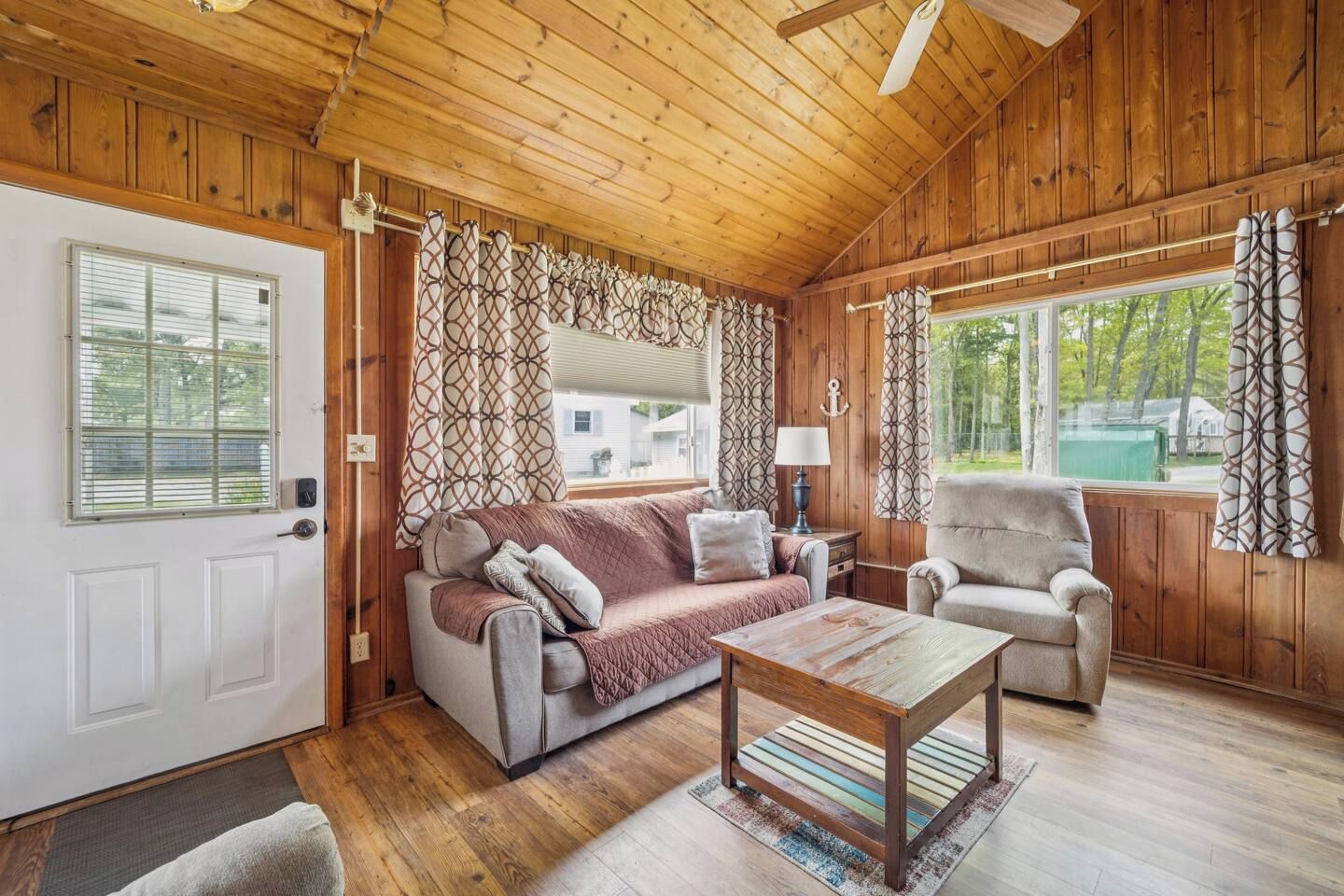 A wooden interior with a sofa, armchair, and a table.