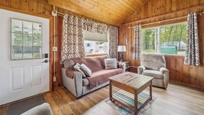 A wooden interior with a sofa, armchair, and a table.