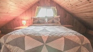 A bedroom with a bed, a window with curtains, and a bedside lamp.
