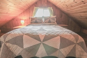 Een slaapkamer met een bed, een raam met gordijnen en een bedlampje.