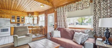 A cozy cabin interior with a dining area, sofa, and a wooden table.