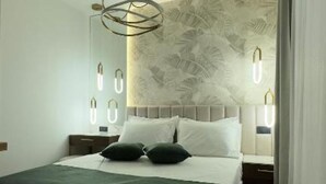 A modern bedroom with a bed, nightstands, and a wall with leaf patterns.