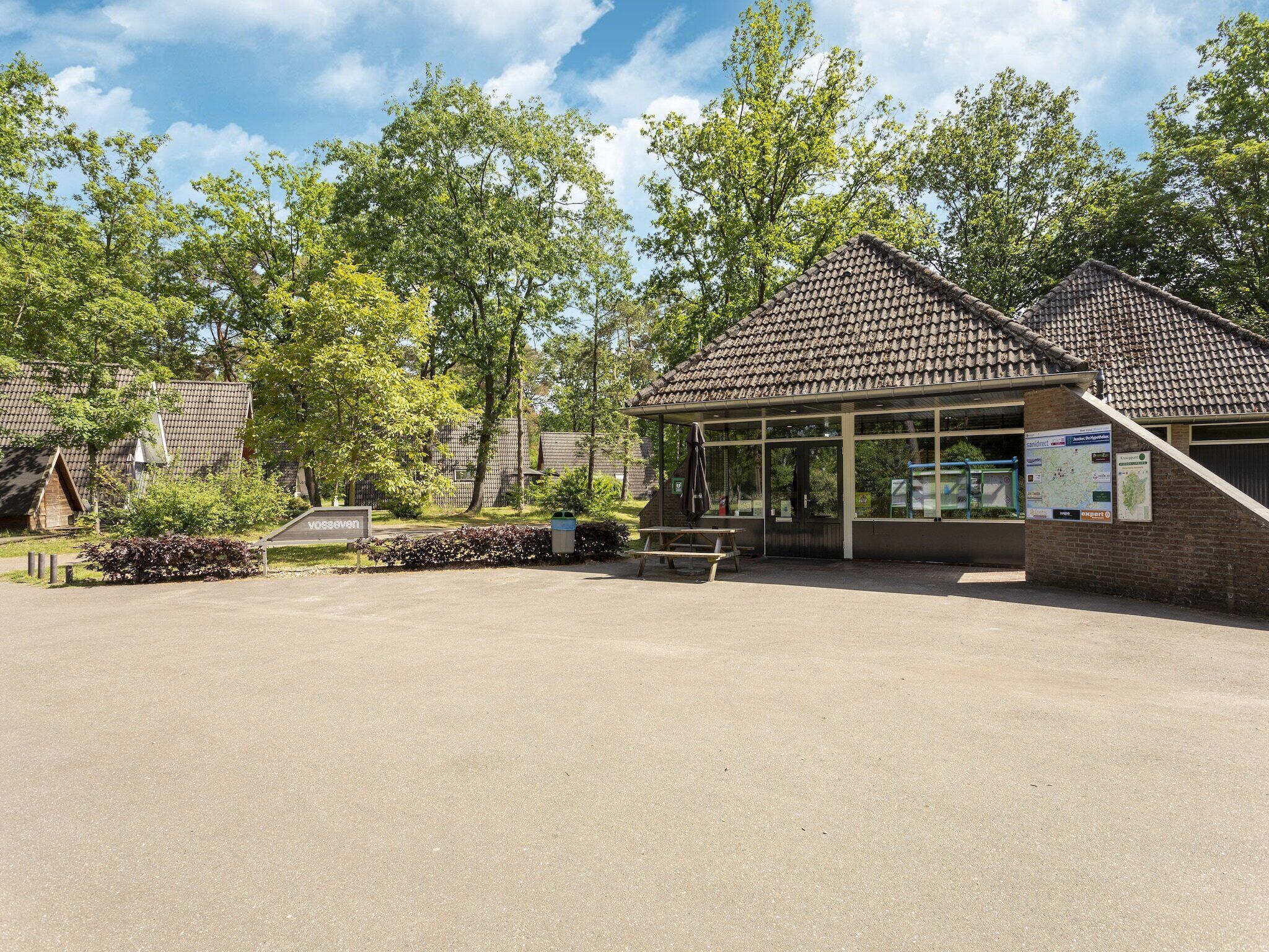 A building with a tiled roof, a bench, and a picnic table in front.