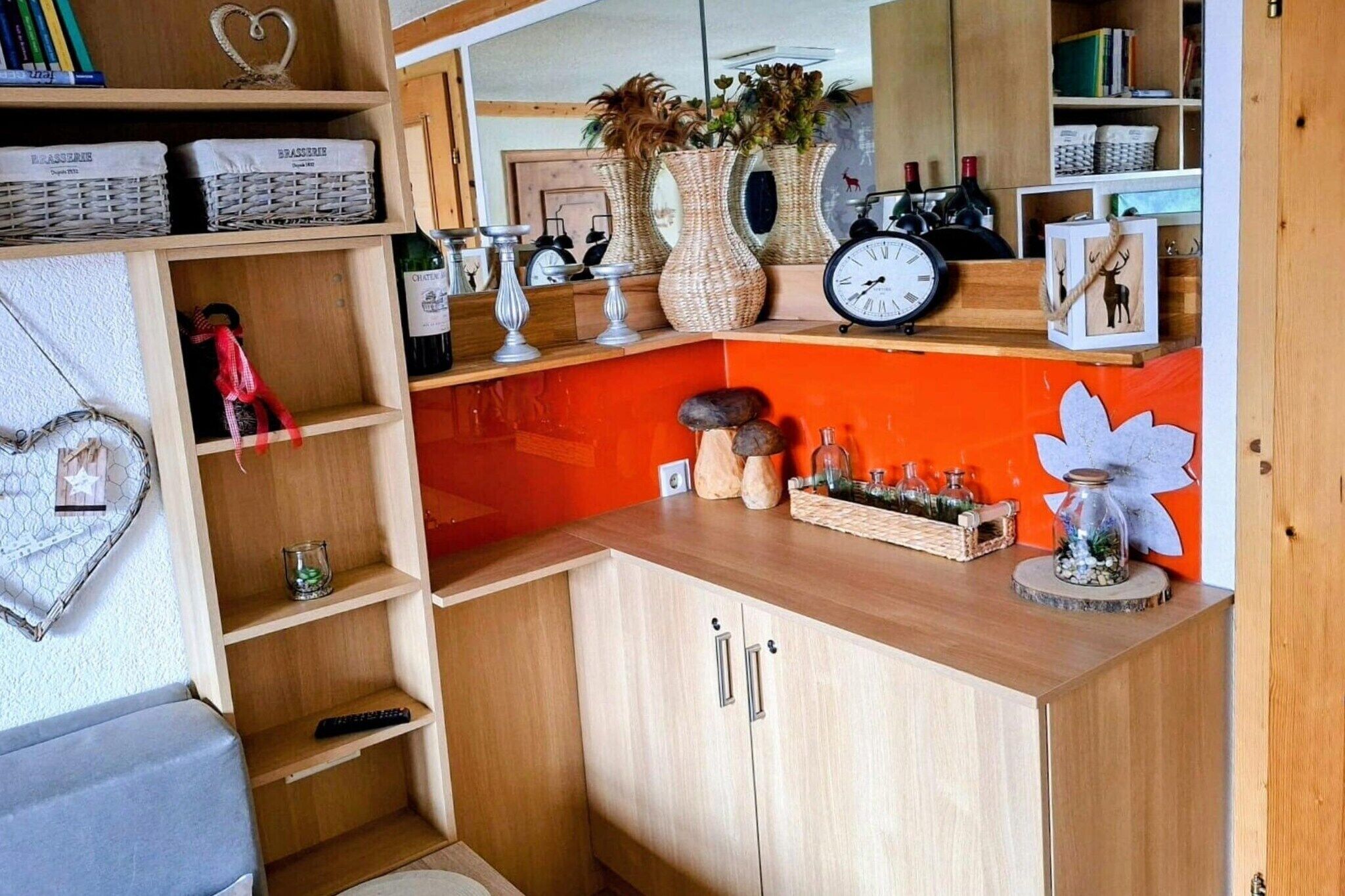 A kitchen with wooden cabinets, wicker baskets, a clock, and decorative items.