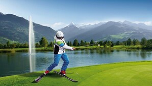 A skier on a green course with a mountain backdrop and a fountain. - Apartment in Walchen near Ski Slopes (Piesendorf - Walchen)