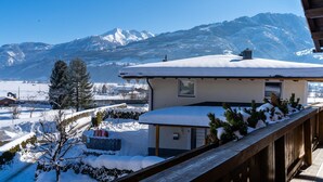 A snow-covered mountain landscape with a house featuring a wooden deck and snow-covered roof. - Apartment in Walchen near Ski Slopes (Piesendorf - Walchen)