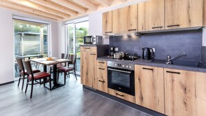 A modern kitchen with wooden cabinets, a built-in oven, and a large window.