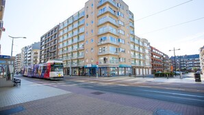 A multi-story residential building with balconies, a tram, and a pedestrian walkway. - Partial Sea View Apartment (Middelkerke)
