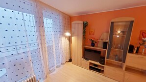 A room with a wooden cabinet, a television, and a plant.